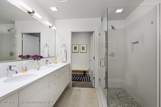 full bathroom with a sink, a shower stall, and double vanity