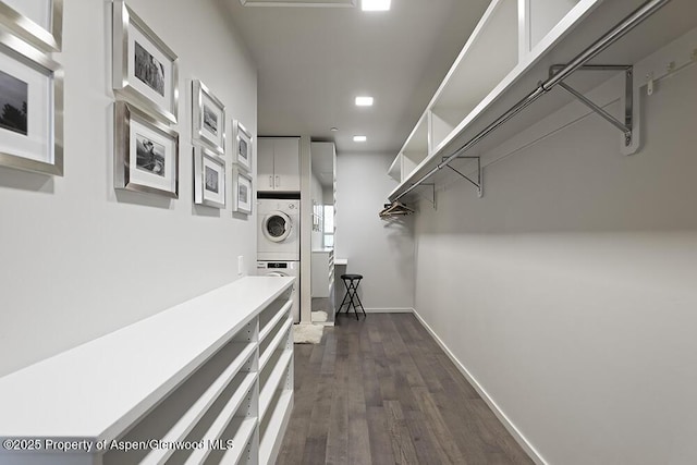 spacious closet with dark wood-style flooring and stacked washer / drying machine