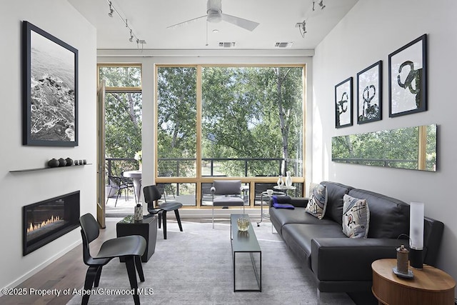 living room with a ceiling fan, rail lighting, visible vents, and a glass covered fireplace