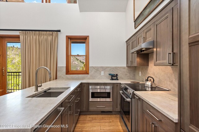 kitchen featuring sink, stainless steel appliances, tasteful backsplash, light hardwood / wood-style flooring, and kitchen peninsula