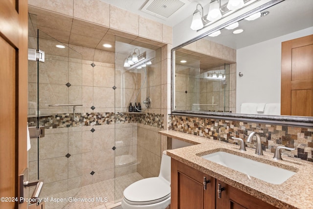 bathroom with vanity, tasteful backsplash, toilet, and a shower with door