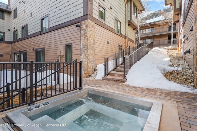 snow covered pool featuring an in ground hot tub