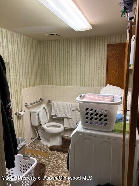 1598 N Yampa Ave, Craig, CO 81625 - bathroom with wallpapered walls, a wainscoted wall, washer and dryer, and tile walls