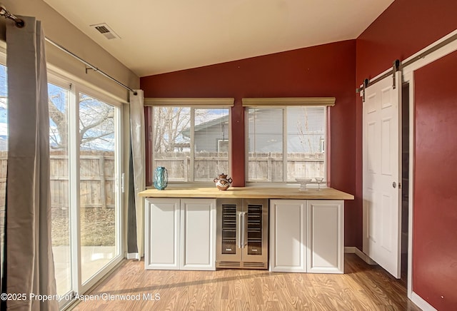 interior space featuring lofted ceiling, beverage cooler, a barn door, and plenty of natural light