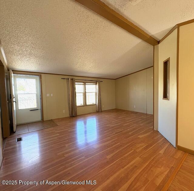 unfurnished living room with crown molding, visible vents, light wood-type flooring, and a textured ceiling