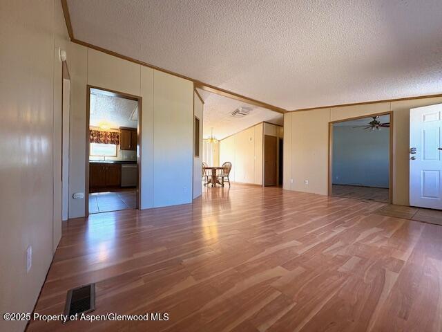 spare room featuring visible vents, a textured ceiling, crown molding, and wood finished floors