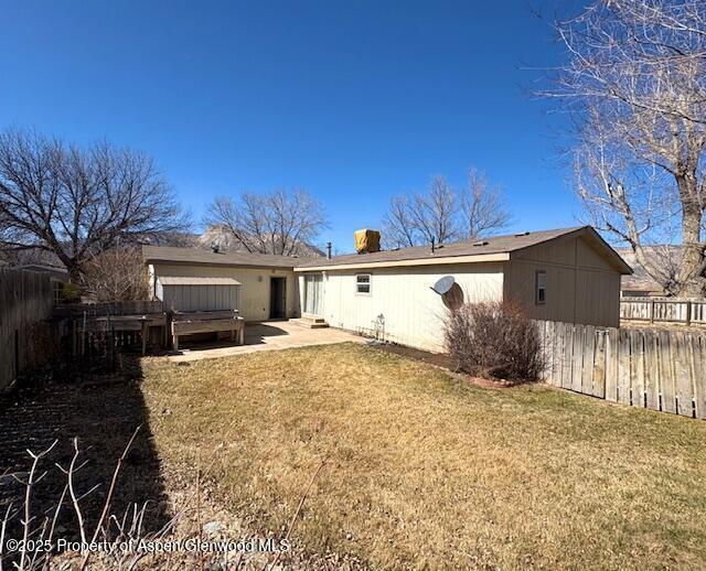 rear view of property featuring fence, a lawn, and a patio area