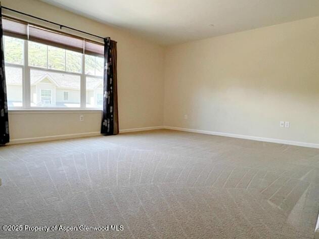 unfurnished room featuring carpet and baseboards