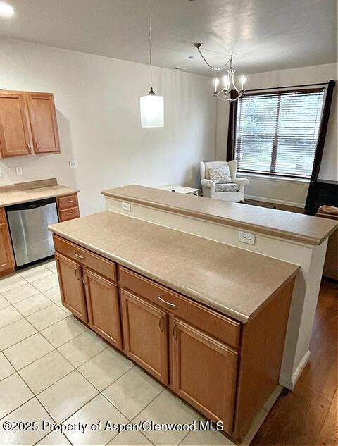 kitchen with pendant lighting, light tile patterned floors, brown cabinetry, a kitchen island, and dishwasher