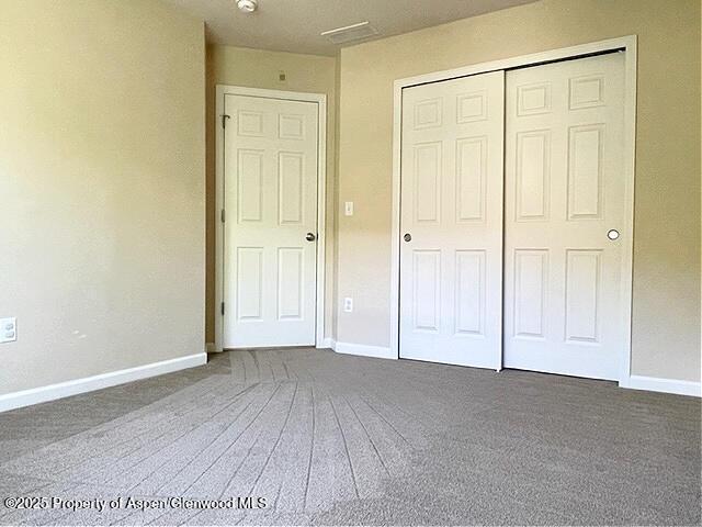 unfurnished bedroom with carpet floors, baseboards, and a closet