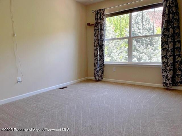 spare room featuring visible vents, baseboards, and light colored carpet