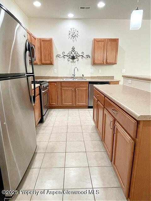 kitchen with brown cabinets, stainless steel appliances, light countertops, visible vents, and a sink