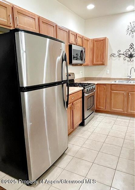 kitchen featuring light tile patterned floors, recessed lighting, a sink, light countertops, and appliances with stainless steel finishes