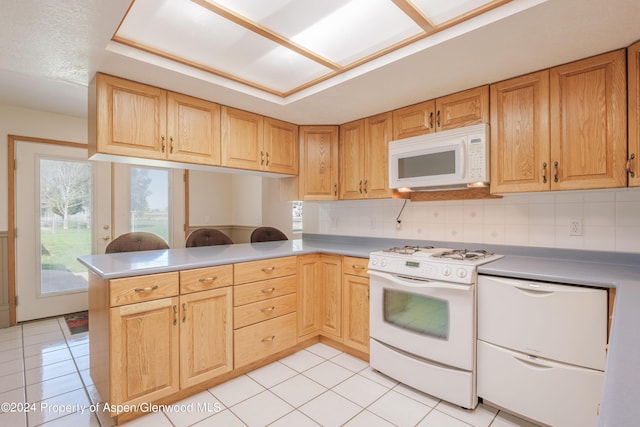 kitchen with white appliances, kitchen peninsula, light tile patterned floors, and tasteful backsplash