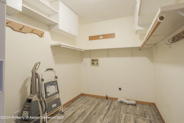 clothes washing area with electric dryer hookup, hookup for a washing machine, cabinets, and light hardwood / wood-style floors