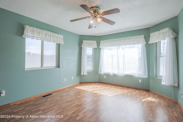 spare room with ceiling fan, wood-type flooring, and a wealth of natural light