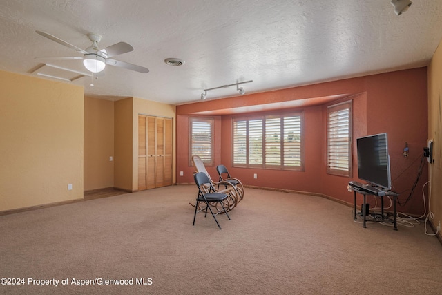 living area with light carpet, a textured ceiling, rail lighting, and ceiling fan