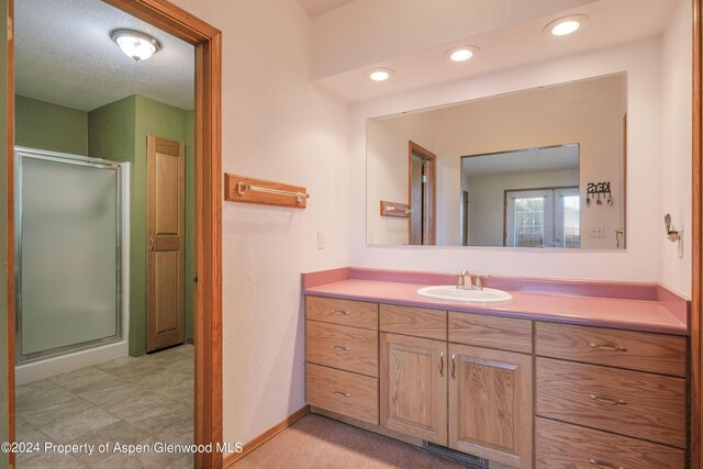 bathroom with vanity, a textured ceiling, and walk in shower