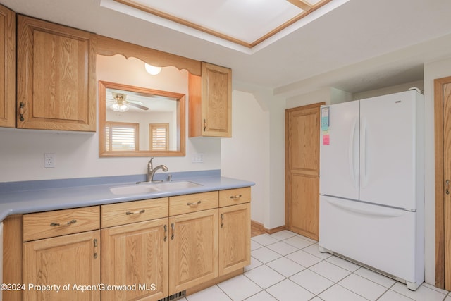 kitchen featuring light brown cabinets, white refrigerator, sink, ceiling fan, and light tile patterned floors