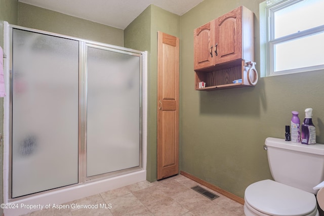 bathroom featuring toilet and a shower with door