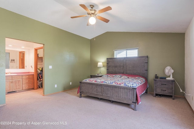 carpeted bedroom with ensuite bath, ceiling fan, sink, and vaulted ceiling