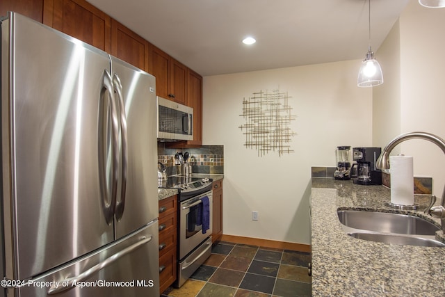 kitchen featuring sink, hanging light fixtures, tasteful backsplash, stone countertops, and stainless steel appliances