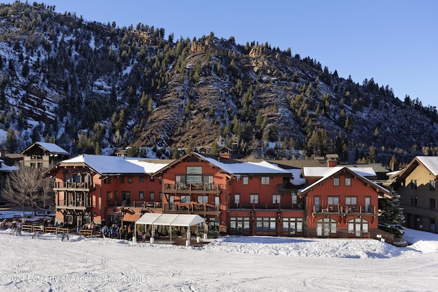 snow covered rear of property with a mountain view