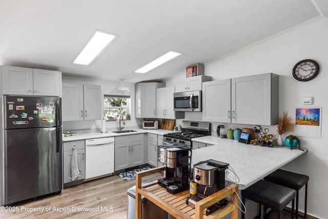 68 E Bonanza Pl, Parachute, CO 81635 - kitchen with appliances with stainless steel finishes, a peninsula, light countertops, vaulted ceiling, and light wood finished floors