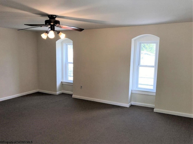 empty room with dark colored carpet and ceiling fan