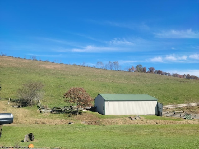 exterior space featuring a rural view, a yard, and an outdoor structure