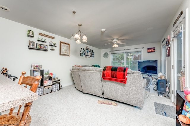 carpeted living room featuring ceiling fan with notable chandelier