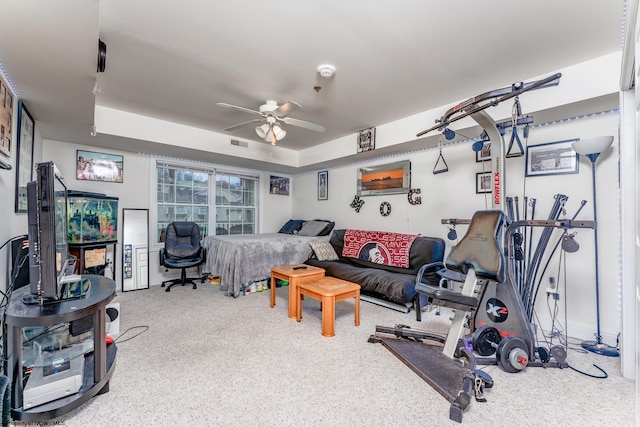 workout area with a tray ceiling and ceiling fan