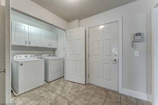 laundry room with cabinets, light tile floors, and washing machine and clothes dryer