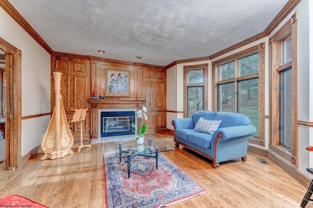 living room featuring crown molding, a textured ceiling, and light wood-type flooring