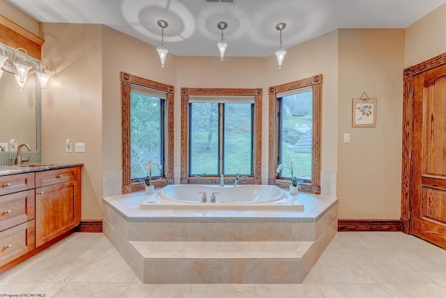 bathroom with a relaxing tiled tub, vanity, and tile patterned flooring