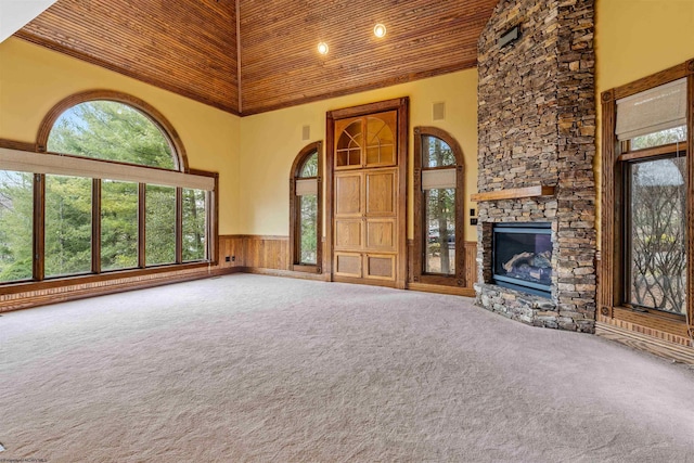 unfurnished living room with wooden walls, carpet flooring, a fireplace, and a high ceiling