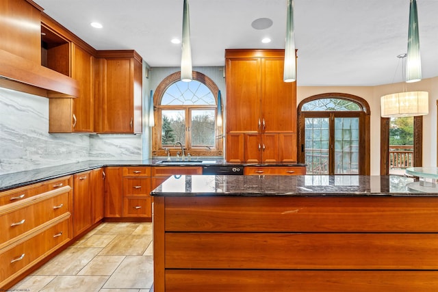 kitchen featuring pendant lighting, dark stone counters, sink, and tasteful backsplash