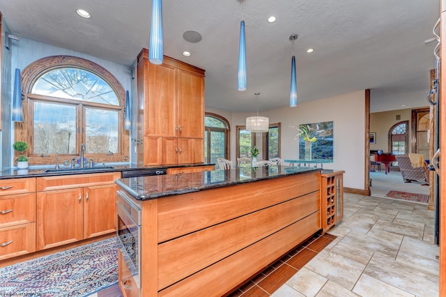 kitchen with sink, a wealth of natural light, dark stone countertops, and light tile flooring