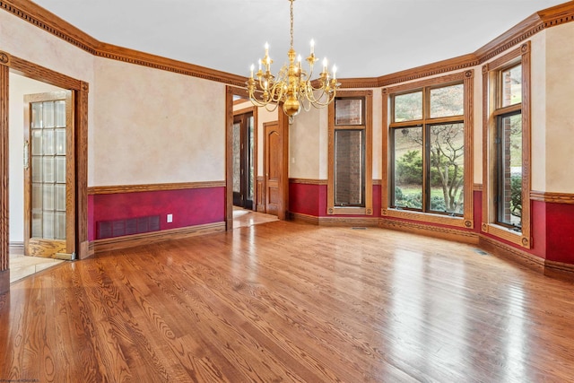 empty room with crown molding, hardwood / wood-style floors, and a chandelier