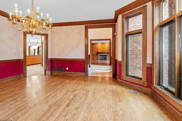 unfurnished room featuring an inviting chandelier, ornamental molding, and light hardwood / wood-style floors