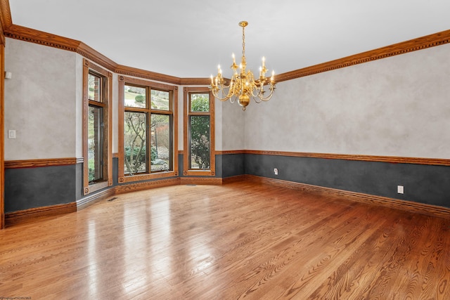 spare room featuring crown molding, light hardwood / wood-style flooring, and a notable chandelier