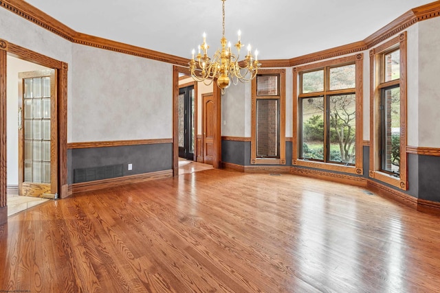 unfurnished dining area featuring hardwood / wood-style floors, a notable chandelier, and ornamental molding