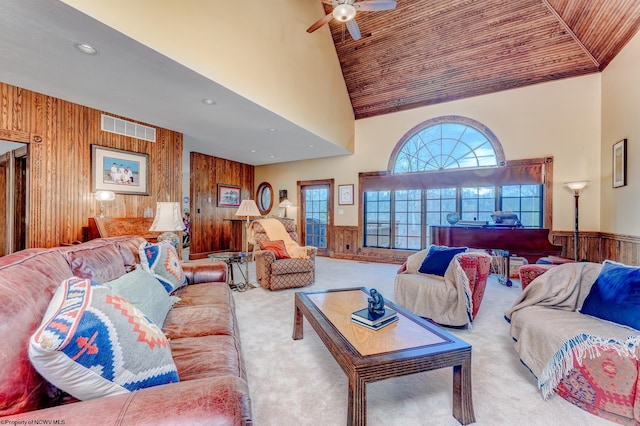 living room with high vaulted ceiling, ceiling fan, wood ceiling, wooden walls, and light carpet