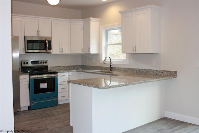 kitchen featuring dark wood-type flooring, stainless steel appliances, white cabinetry, and light stone countertops