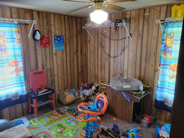 game room with wood walls, carpet floors, and ceiling fan