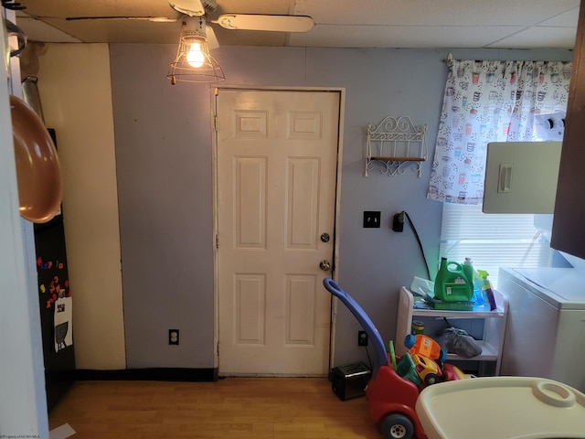 interior space featuring a paneled ceiling, ceiling fan, light wood-type flooring, and washer / dryer