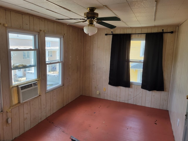 spare room featuring ceiling fan and wooden walls