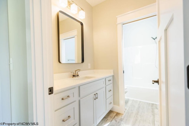 full bathroom featuring  shower combination, toilet, vanity, and hardwood / wood-style floors