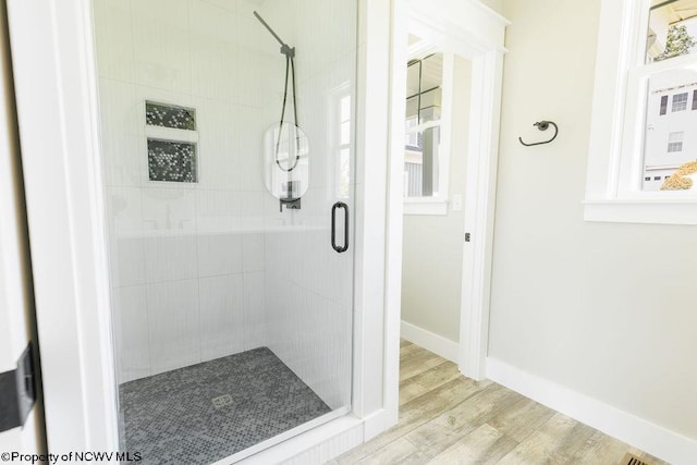 bathroom with a shower with shower door and hardwood / wood-style flooring