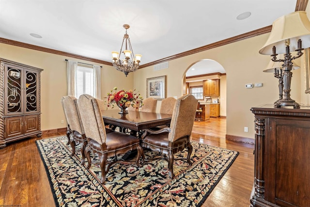 dining area featuring dark hardwood / wood-style flooring, ornamental molding, and a chandelier